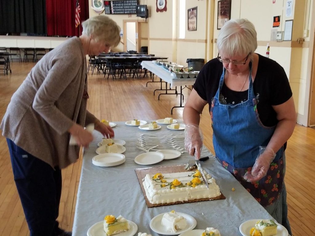 Kathy and Laura cutting cake at 2019 Senior Luncheon